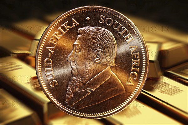 Close-up of a Krugerrand gold coin, in the background blurred gold bars (composing)