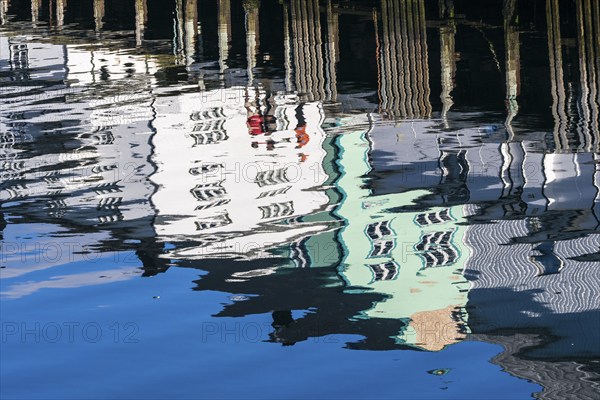 Pier at harbor in Henningsvær, reflections of wooden houses in the calm water, Austvagøy, Lofoten,