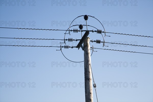 Close up of electricity cables and telegraph pole against blue sky, UK