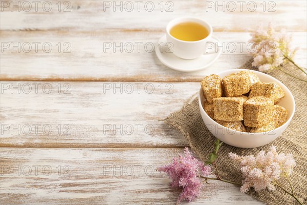 Traditional turkish delight (rahat lokum) in white ceramic plate with cup of green tea on a white