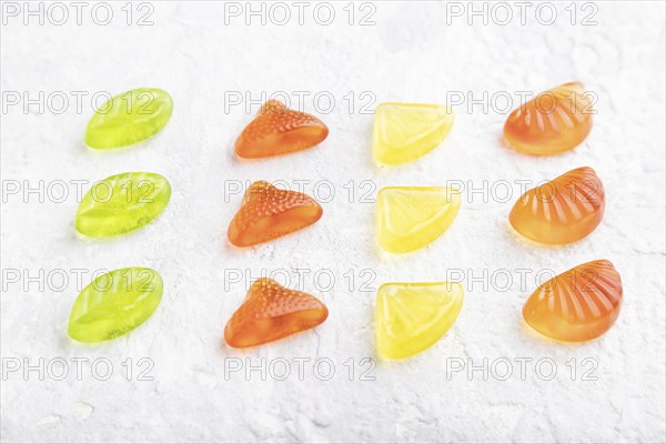 Various fruit jelly candies on gray concrete background. side view, close up