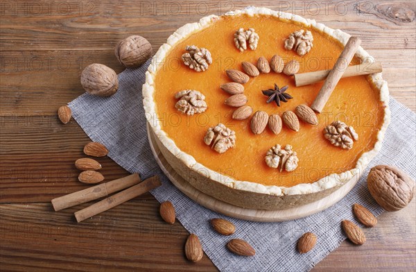 Traditional american sweet pumpkin pie decorated with nuts, on brown wooden background. close up,