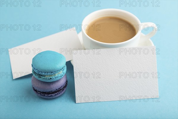White paper business card mockup with blue and violet macaroons and cup of coffee on blue pastel