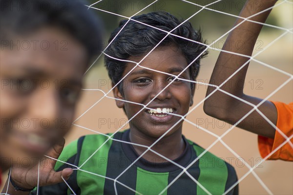 Laughing boys looking through goal net, football, Parade Ground, Fort Cochin, Kochi, Kerala, South