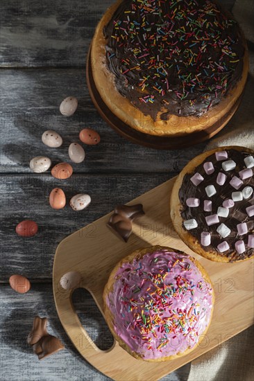 Homemade glazed and decorated easter pies with chocolate eggs and rabbits on a gray wooden