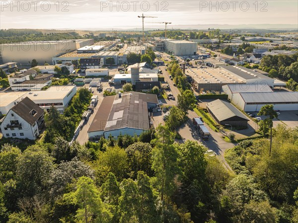 Industrial area with various buildings and a crane in the background, trees along the streets,