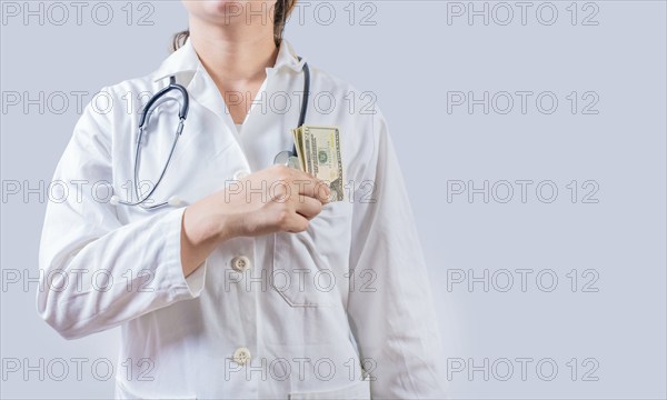 Unrecognizable doctor putting bribe money in pocket isolated. Dishonest female doctor putting money