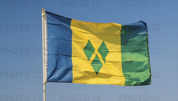 The flag of the Grenadines flutters in the wind, isolated against a blue sky