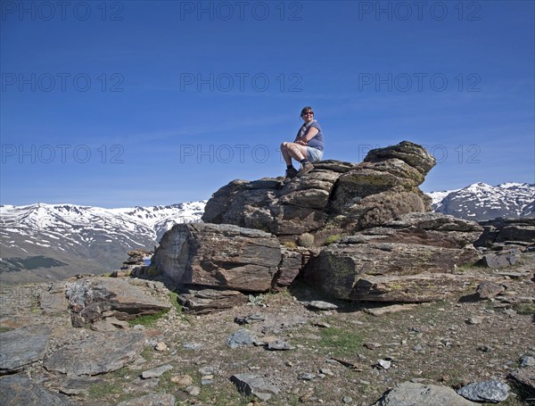 Woman sitting on rocky outcrop in the Sierra Nevada Mountains in the High Alpujarras, near