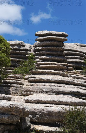 Round rock formations under a blue sky with scattered clouds and green vegetation, Karst Mountains,