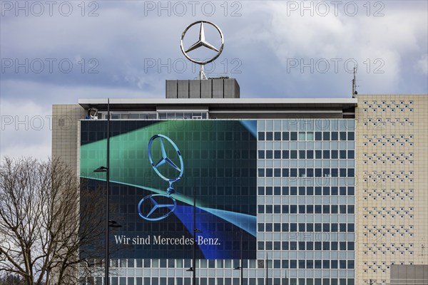 Mercedes star in front of dark clouds, office building at the headquarters of Mercedes-Benz Group