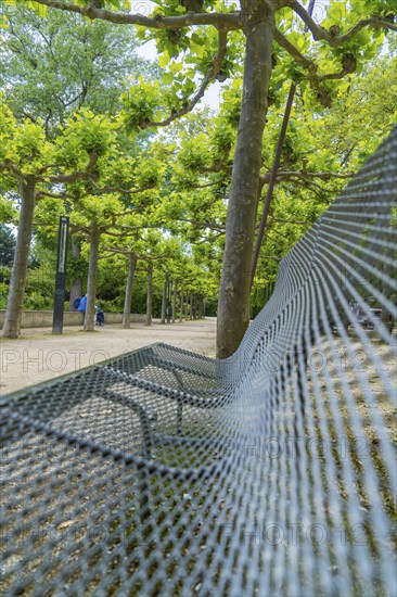 Corrugated metal bench under shady trees in an avenue, Böblingen, Germany, Europe