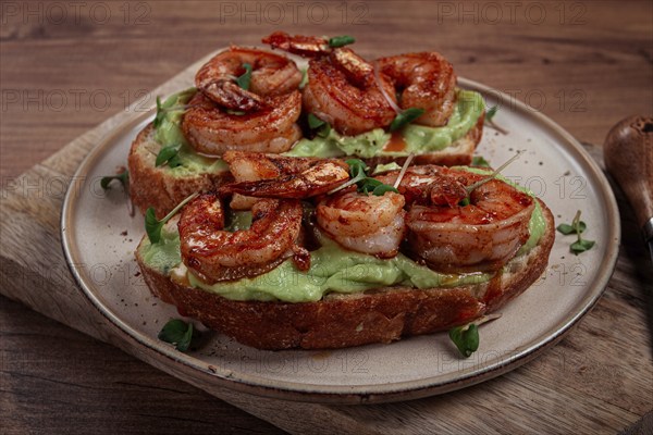 Sandwiches with avocado and caramelized shrimp, micro-greens, breakfast, on a plate, top view,