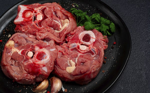 Raw steak, calf's neck on the bone, fresh meat, on a black plate, top view, no people