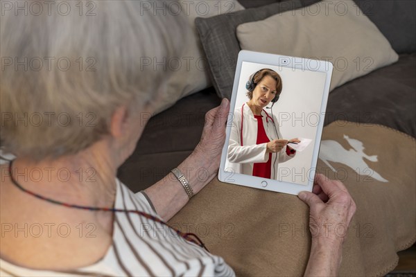 Symbolic image of telemedicine, patient speaking to a doctor in a video conference from home