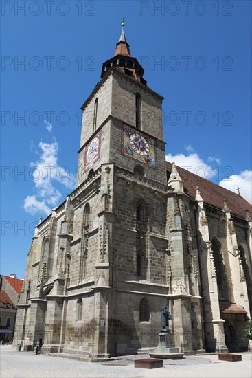Gothic church with tower under clear blue sky, large clock visible, Black Church, Old Town, Brasov,