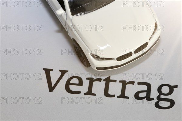 Symbolic image of car insurance: model car with contract documents