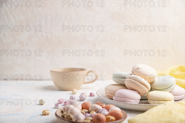Colored zephyr or marshmallow with cup of coffee and dragees on white concrete background and