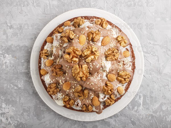 Homemade cake with milk cream, cocoa, almond, hazelnut on a gray concrete background with orange