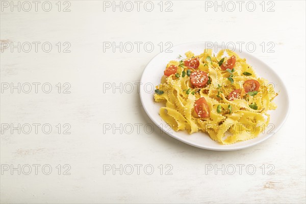 Reginelle semolina pasta with tomato, eggs, sesame and microgreen sprouts on a white wooden