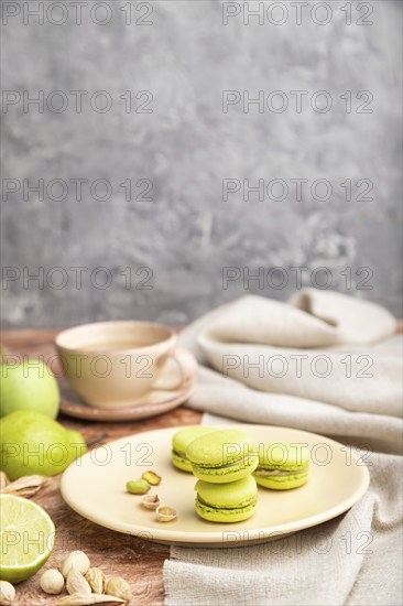 Green macarons or macaroons cakes with cup of coffee on a brown and gray concrete background and