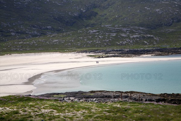 A couple walking in the distance on sandy beach in Halaman bay, Barra, Outer Hebrides, Scotland, UK
