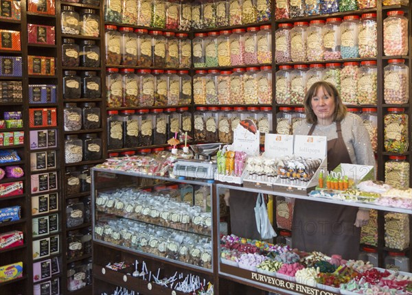 Interior with shop assistant and jars of traditional sweets, Olde Sweet Shop, Ipswich, Suffolk,