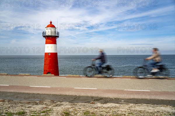 North Sea dyke near Westkapelle, Westkapelle Laag lighthouse, cyclists on the Zeeuwse Wind Route
