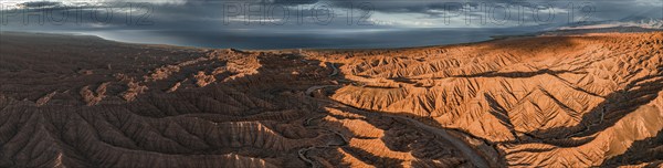 Panorama, landscape of eroded hills, badlands at sunset, Issyk Kul Lake in the background, aerial
