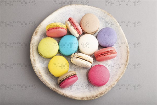 Multicolored macaroons on ceramic plate on gray pastel background. top view, close up, still life,