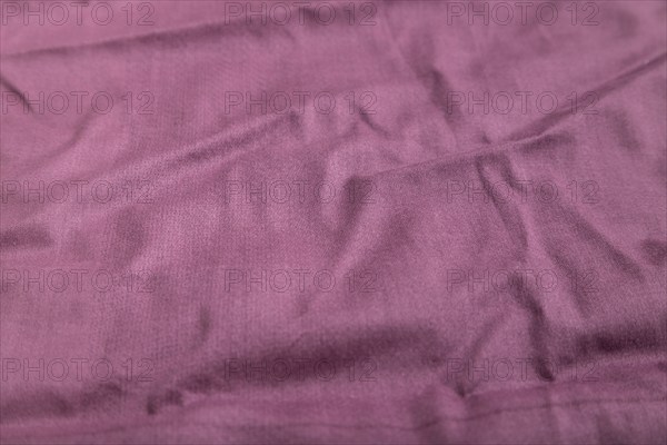Fragment of smooth cotton purple tissue. Side view, natural textile background and texture