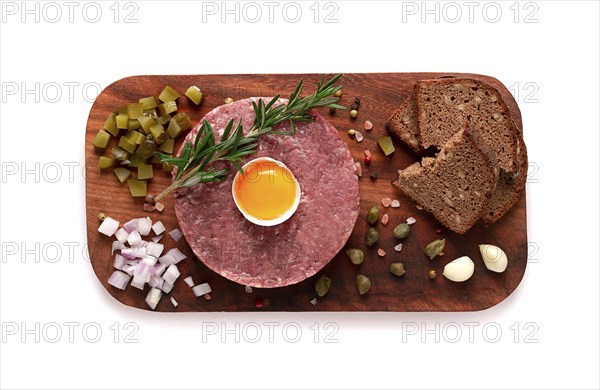 Beef tartare, with egg, capers, gherkins and bread, on a white background, top view, close up,