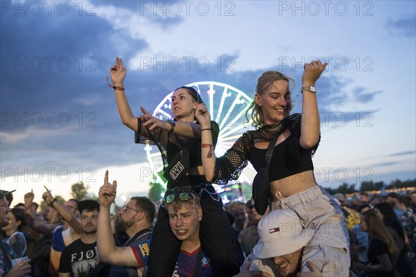 Festival visitors celebrate on shoulders during Ski Aggu's performance in front of the Ferris wheel