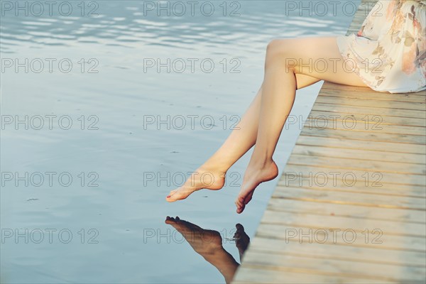 Barefoot female feet above calm water