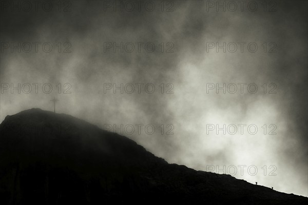 Summit of the Sulzfluh with ascending mountaineers and dramatic cloudy sky, Tschagguns, Rätikon,