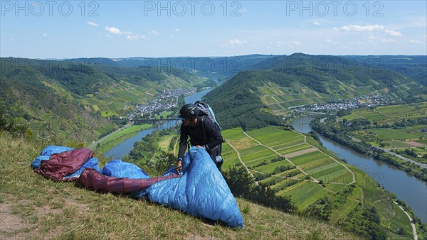 Paraglider prepares on the hill, with a wide view of the river and valleys, Paragliding, Bremm,