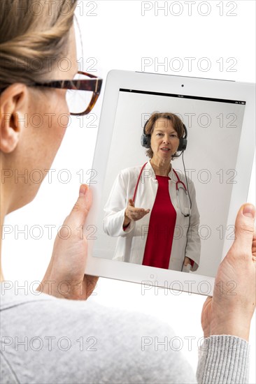 Symbolic image of telemedicine, patient speaking to a doctor in a video conference from home