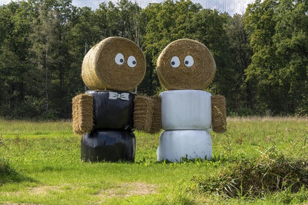 Straw bale dolls, figures, as wedding couple, in front of a house near Arcen, Netherlands,