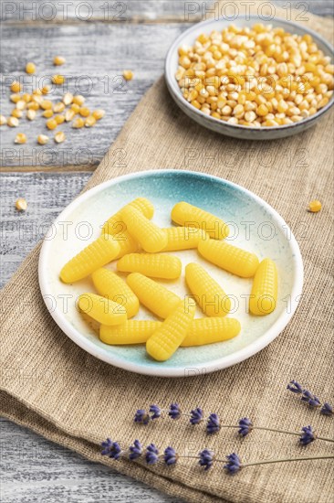 Jelly corn candies on gray wooden background and linen textile. close up, side view