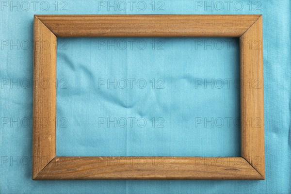 Wooden frame on smooth cotton blue tissue. Top view, flat lay, natural textile background and