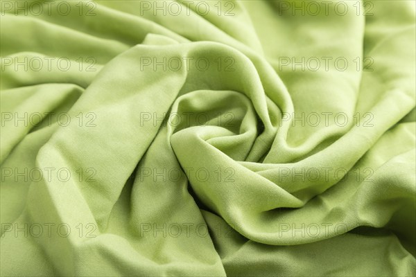 Fragment of green linen tissue. Side view, natural textile background and texture. wave concept,