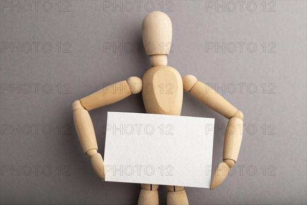 Wooden mannequin holding blank poster on gray pastel background. copy space, isolated, presentation