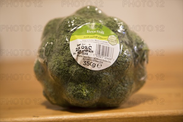 Broccoli head wrapped in plastic film with Tesco product label close up