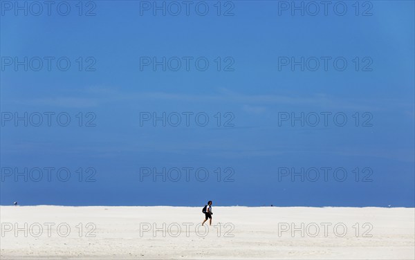 DEU, 18.06.2020, A holidaymaker walks through the knee sand on the beach of the island of Amrum,