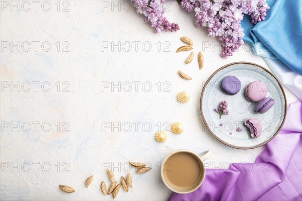 Purple macarons or macaroons cakes with cup of coffee on a white concrete background and