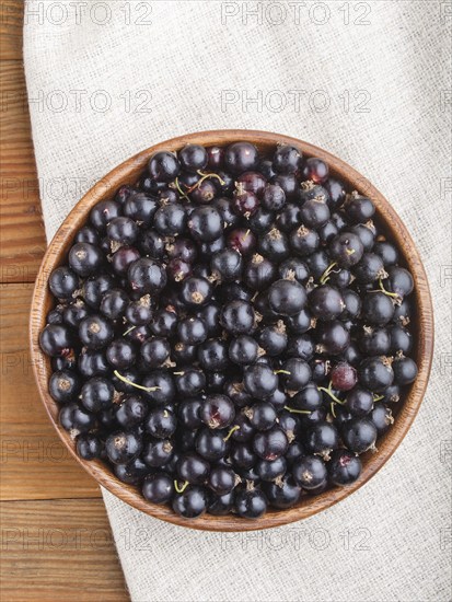 Fresh black currant in wooden bowl on wooden background. top view, flat lay, close up