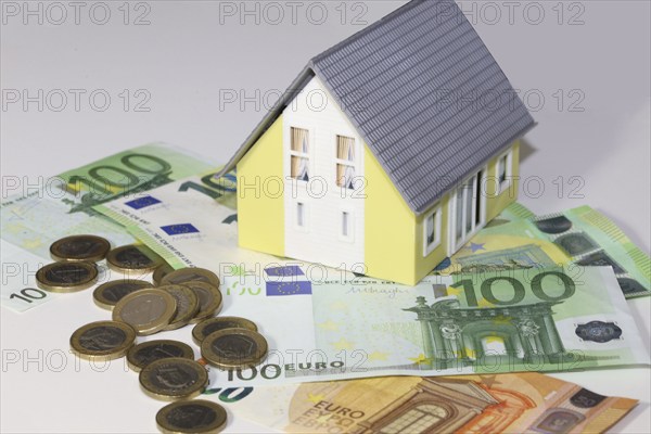 Concept photo with model house, euro notes and coins