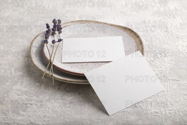 White paper invitation card, mockup with lavender on ceramic plate and gray concrete background.