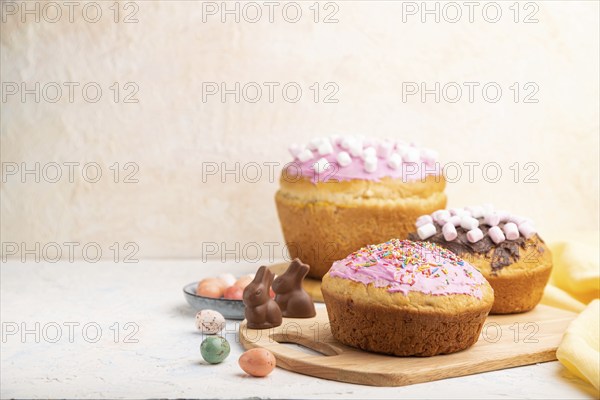 Homemade glazed and decorated easter pies with chocolate eggs and rabbits on a white concrete