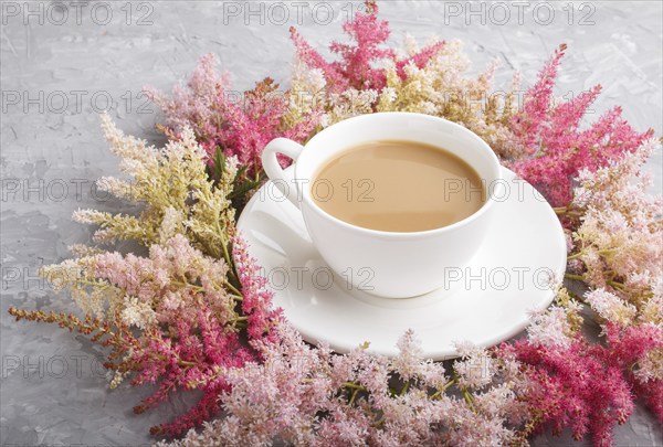 Pink and red astilbe flowers and a cup of coffee on a gray concrete background. Morninig, spring,